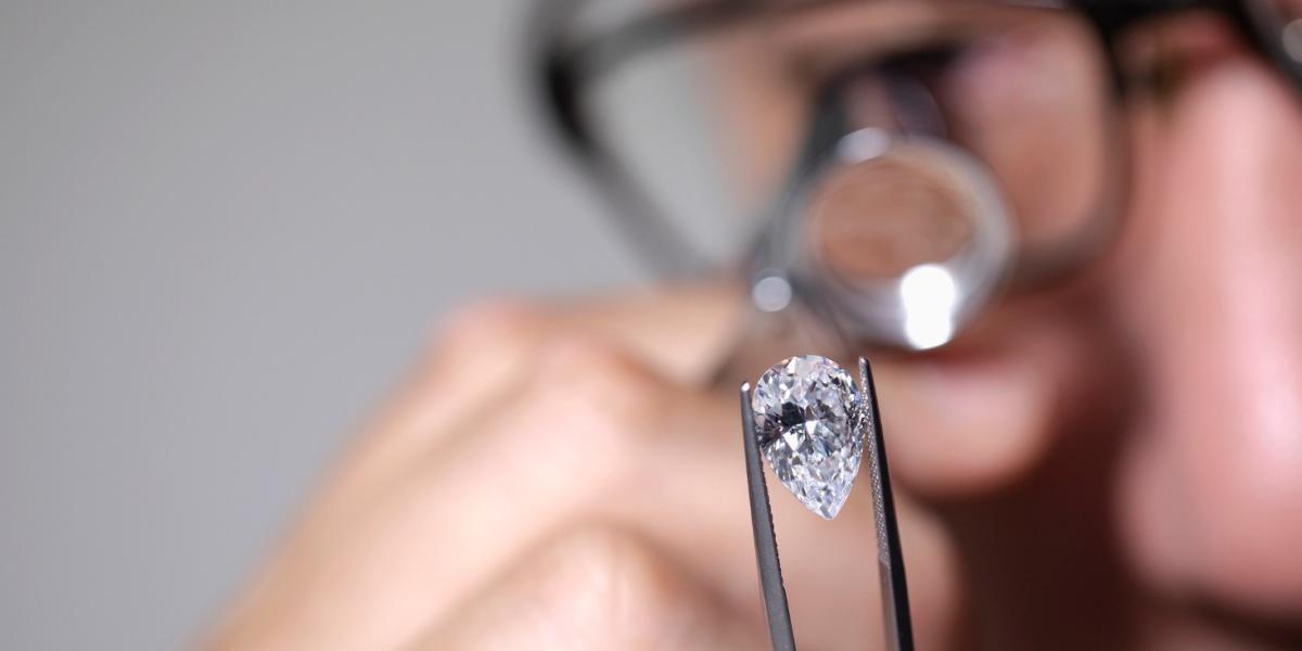 Jeweller inspecting a pear-shaped diamond with a loupe for quality and clarity