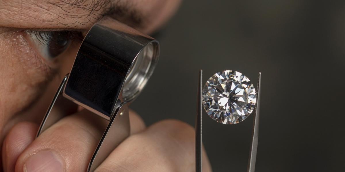 A jeweller is examining a lab-grown diamond through a loupe.